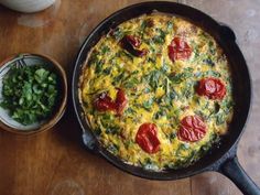 an omelet with tomatoes and spinach in a cast iron skillet on a wooden table