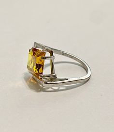 This Vintage 10k White Gold Yellow Sapphire Ring is magnificent! The ring showcases a Emerald set in a four prong setting The Sapphire stone has beautiful color. The stone measures approximately 10mm x 12mm = 6.84 carats The setting is beautiful with a unique style The ring is marked U - 10k Weight- 3.61g Size-7 Formal Citrine Rings With Brilliant Cut, Formal Square Cut Birthstone Ring In Fine Jewelry Style, Fine Jewelry Square Cut Birthstone Ring For Formal Occasions, Yellow Emerald Cut Diamond Ring, Square Cut Birthstone Ring For Formal Events, Square Cut Birthstone Ring For Formal Occasions, Formal Square Cut Birthstone Ring, Formal Princess Cut Topaz Ring With Prong Setting, Estate Hallmarked Jewelry For Anniversary