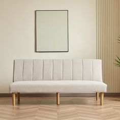 a white couch sitting on top of a wooden floor next to a potted plant