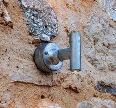 a close up of a light on a stone wall with dirt and rocks in the background