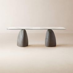 the table is made out of concrete and has an oval shaped base with two small round bases