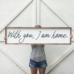 a woman is holding up a sign that says, with you, i am home