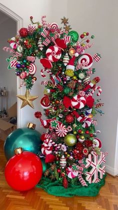 a christmas tree decorated with candy canes, ornaments and balls on a wooden floor