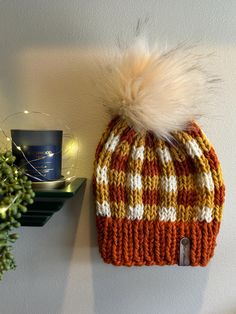 a knitted hat hanging on the wall next to a candle