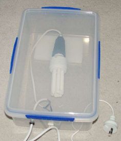 an electronic device in a plastic case on the floor with wires and plugs attached to it