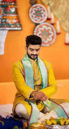 a man sitting on the ground with food in front of him and wearing a yellow outfit