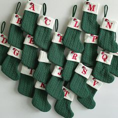 christmas stockings with letters are arranged in rows on a white surface, hanging from hooks