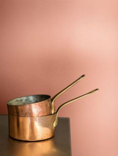 two metal pots and spoons sitting on top of a table