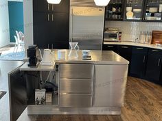 a kitchen with stainless steel counter tops and cabinets in the center, surrounded by dark wood flooring