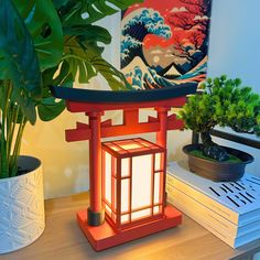 a red lantern sitting on top of a table next to a potted plant