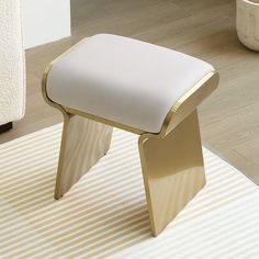 a white and gold stool sitting on top of a rug