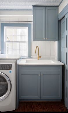 a washer and dryer in a small room with blue cabinets on the walls