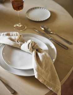 a white plate topped with a napkin next to a wine glass