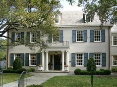 a large white house with blue shutters on the front