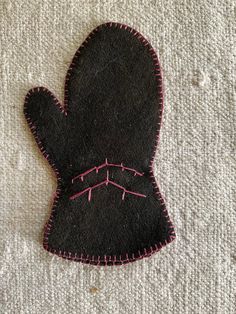 a black mitt with pink stitching on it sitting on top of a white blanket