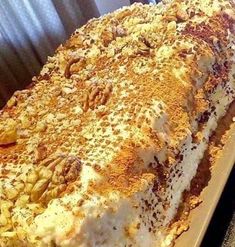 a large piece of cake sitting on top of a pan covered in frosting and nuts