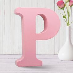 the letter p is painted pink next to a vase with flowers