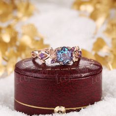 a ring is sitting on top of a box in the snow with gold leaves around it