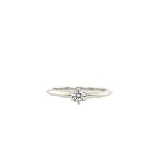 a white gold ring with a single diamond in the center, on a white background