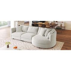 a large white couch sitting on top of a wooden floor next to a table and chair