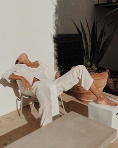 a woman sitting on a chair in front of a potted plant with her eyes closed