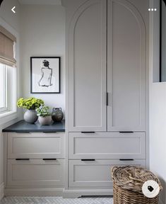 a kitchen with white cabinets and black counter tops next to a basket on the floor