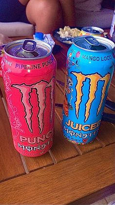 two cans of monster energy drink sitting on a table