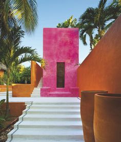 there is a pink building with steps leading up to it and palm trees in the background