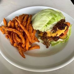 a hamburger and french fries on a white plate with a marble table in the background