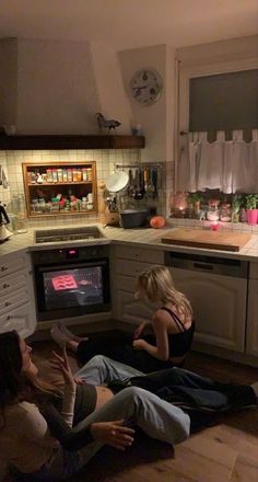 three women sitting on the floor in a kitchen