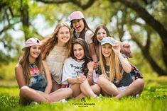 a group of young women sitting next to each other on top of a lush green field