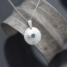 Handmade Blue Topaz Necklace, round sterling silver with blue cabochon gemstone set pin a dome form with a subtle hammered texture.  * Natural blue Topaz gemstone, 'London Blue' colour, 4mm diameter * Sterling Silver * December birthstone, December birthday pendant * Supplied with a regular 44cm (18") fine trace diamond cut sterling silver chain * Boxed ready for gifting A handmade gemstone pendant made to order - You'll receive a Topaz pendant like the example in the photos www.iancaird.com Ins Chain Ideas, Blue Topaz Pendant Necklace, Birthday Pendant, Blue Topaz Necklace, Metal Clay Jewelry, Blue Topaz Pendant, Topaz Pendant, Garnet Bracelet, Jewellery Gifts