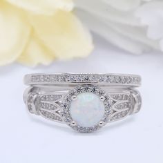 an opal and diamond ring set on top of each other with flowers in the background