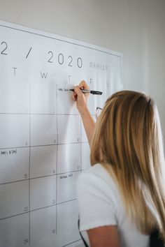 a woman is writing on a calendar