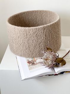 an open book on top of a white table next to a planter and a flower