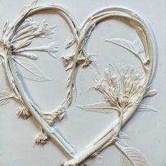 two hearts shaped like flowers on a white surface with leaves and stems attached to them