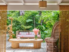 an outdoor living area with wicker furniture and tropical trees in the background, along with large bamboo screens