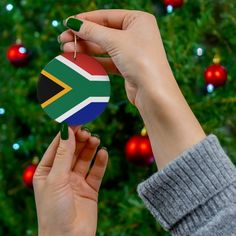 two hands holding a christmas ornament with the flag of australia hanging from it