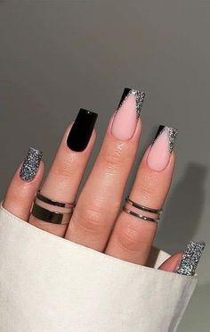 a woman's hand with black and pink manicures on her nails, in front of a gray background