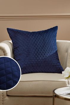 a blue pillow sitting on top of a couch next to a vase with white flowers