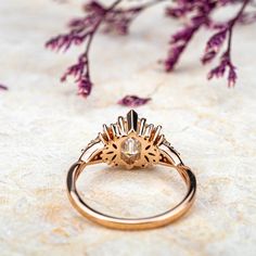 a gold ring sitting on top of a table next to purple flowers