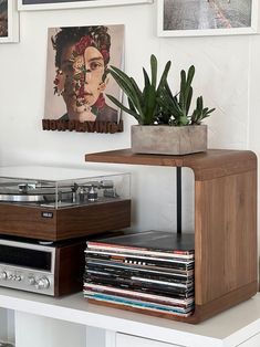 a record player sitting on top of a white shelf next to a potted plant