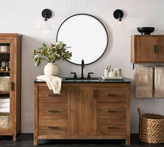 a bathroom with wooden cabinets and a round mirror on the wall above the sink,