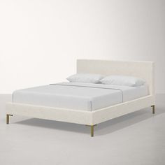 a bed with white linen and gold legs