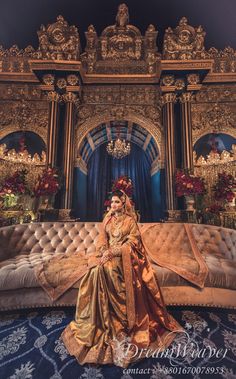 a woman sitting on top of a couch in front of a blue and gold wall