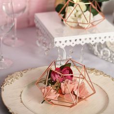 two small vases with flowers in them sitting on a white and pink table cloth