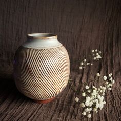 a white vase sitting on top of a wooden table next to baby's breath flowers