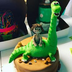 there is a cake decorated to look like a dinosaur with a boy on it's back