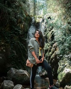 a woman standing in front of a waterfall