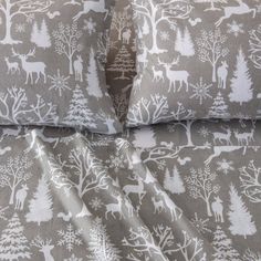 a bed with two pillows covered in grey and white deer print sheets, along with matching pillow cases